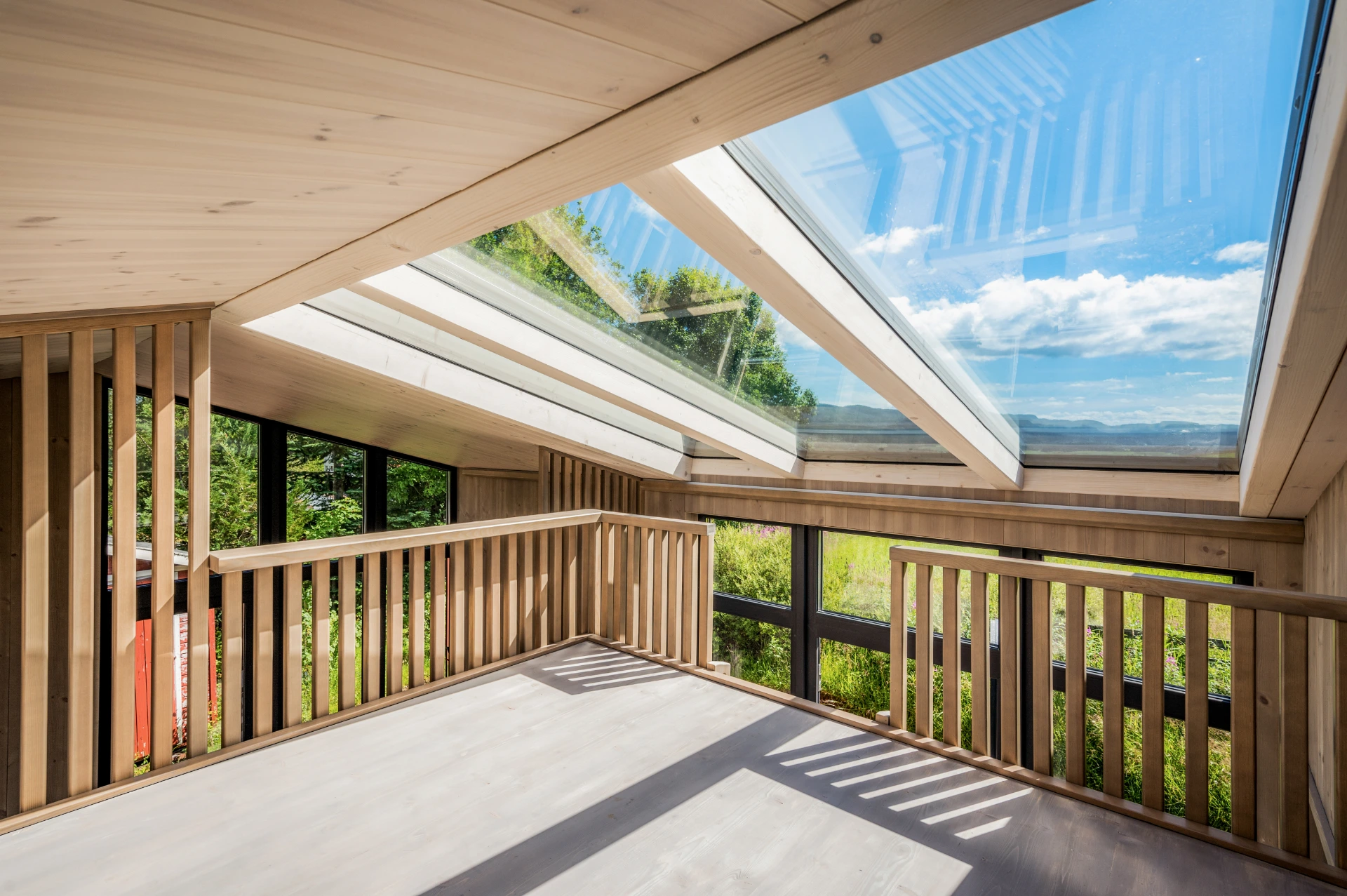 Überdachte Terrasse mit Glasdach und Holzgeländer, Blick über die Landschaft